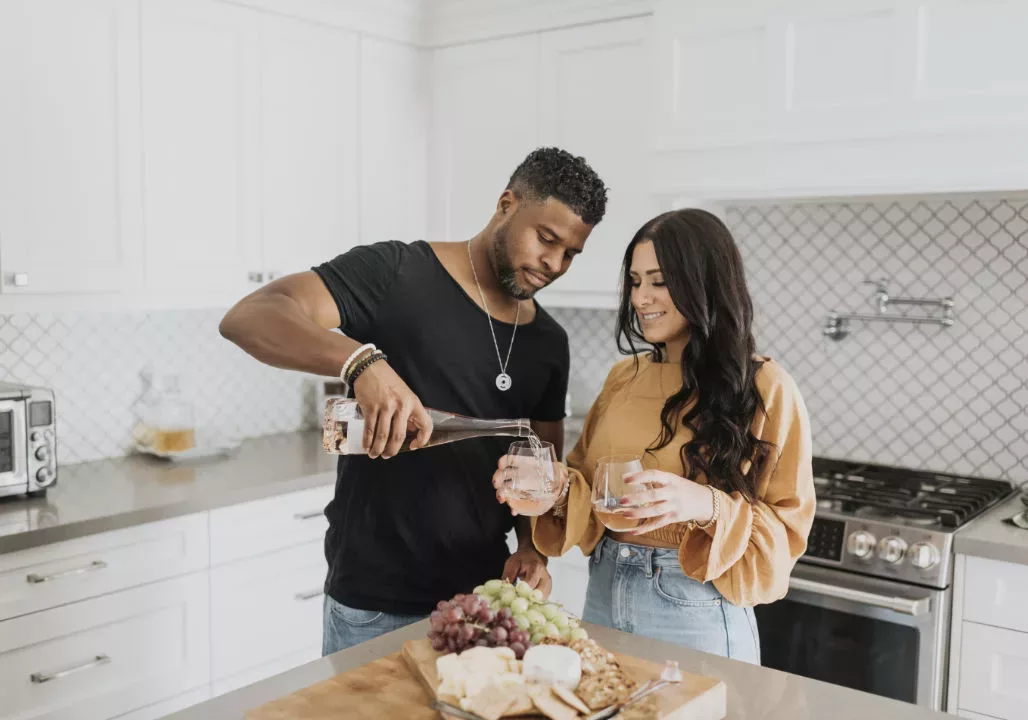 Couple in kitchen pouring wine