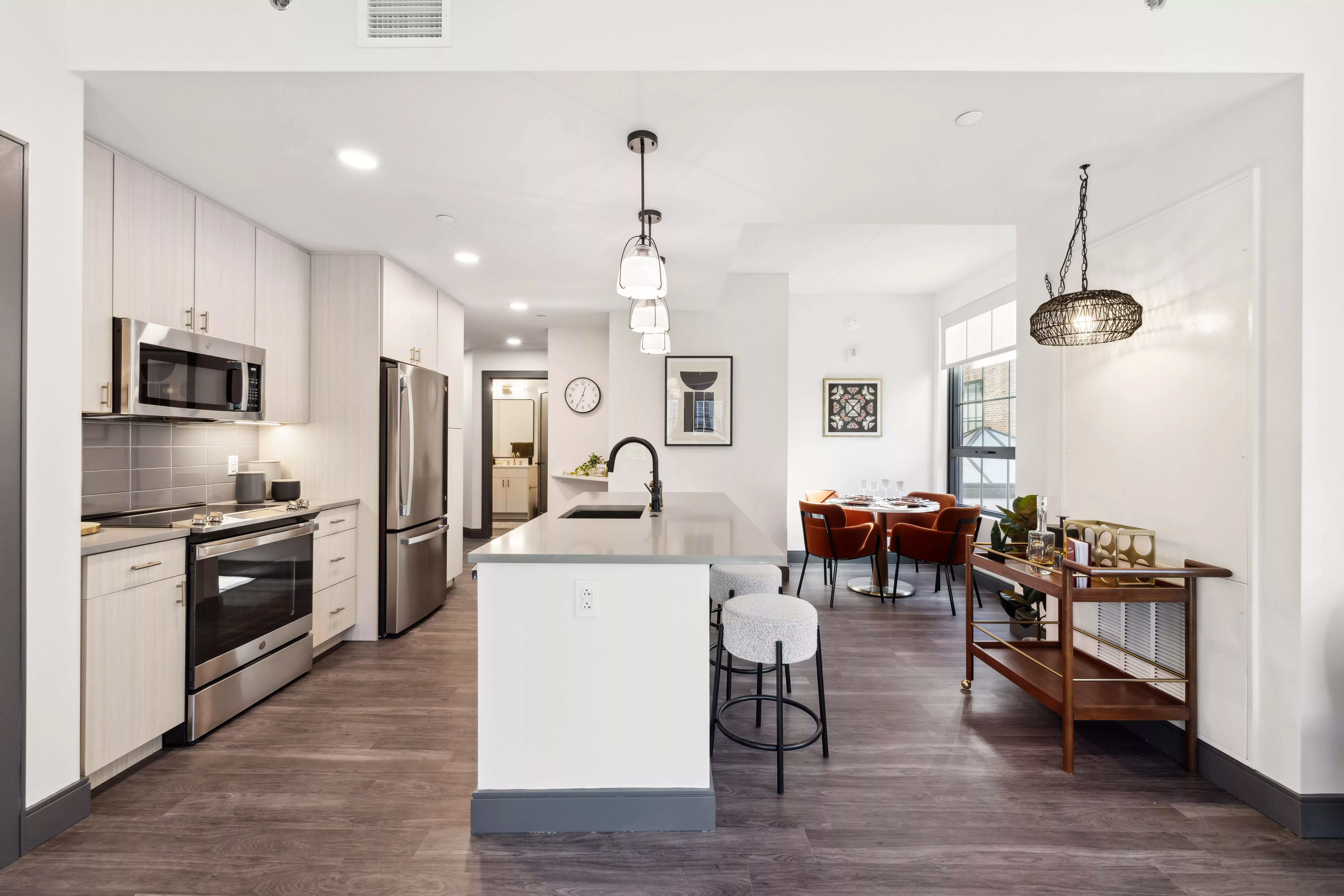Kitchen with light color cabinets, dark wood-style floors, white walls, and hanging lights