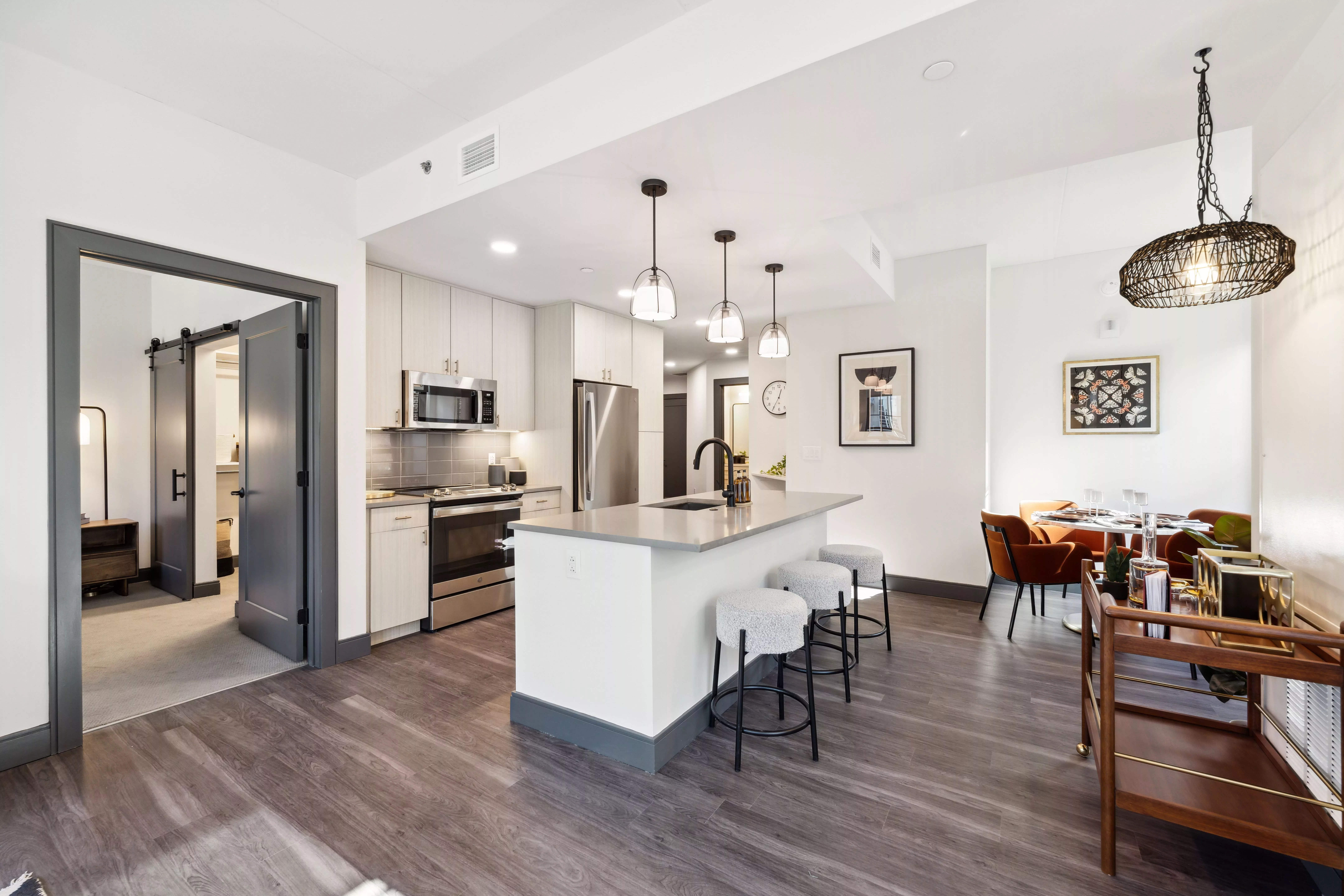 Kitchen with light colored cabinets, dark wood-style floors, and center island with lights hanging above