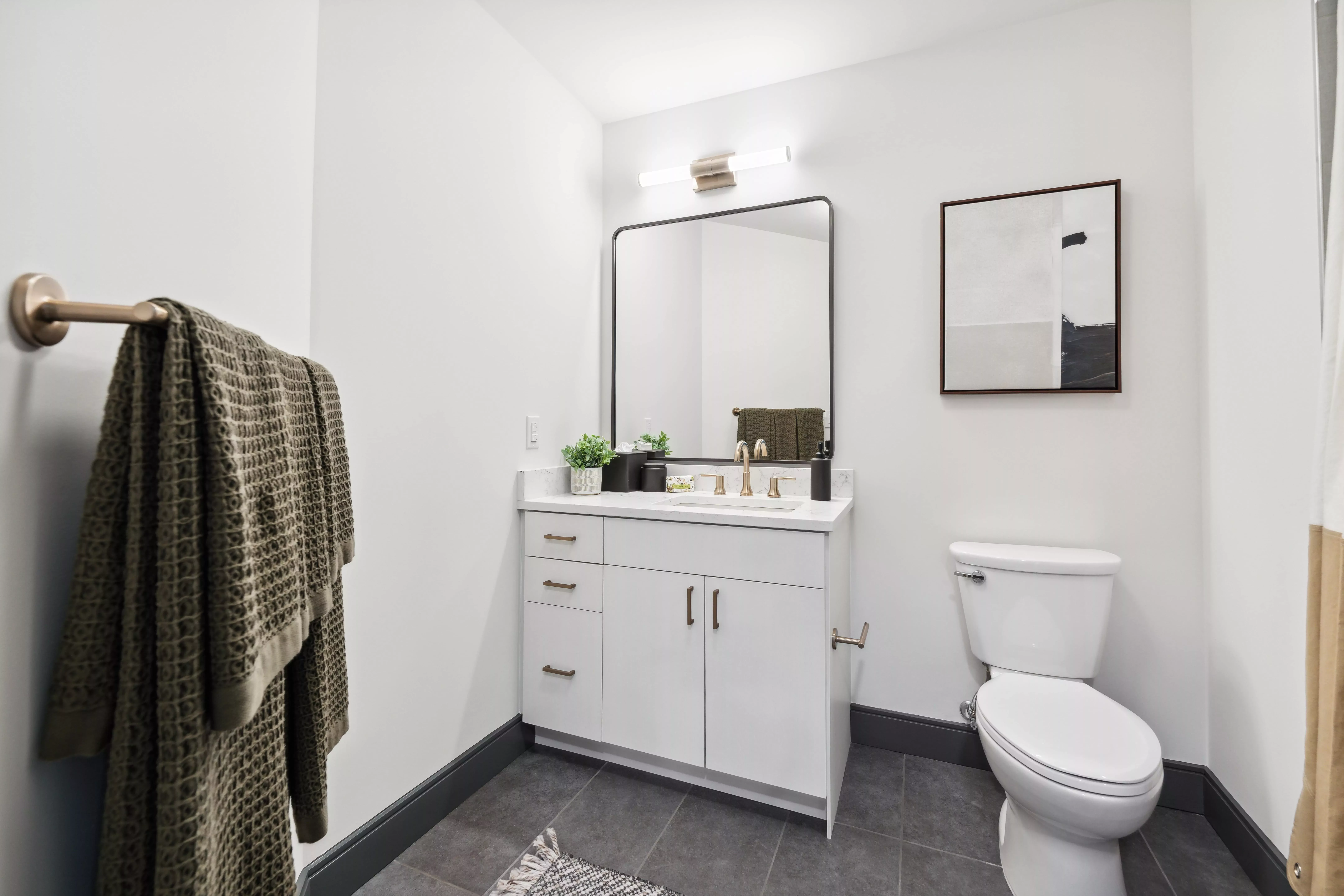 Bathroom with white walls, dark gray tile floor, and white cabinets beneath the vanity,