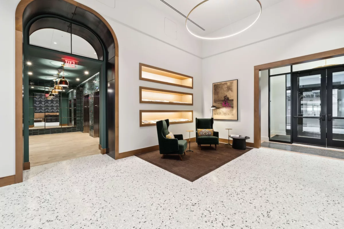 Seating area with green chairs and entrance to the elevator lobby with dark green tile walls