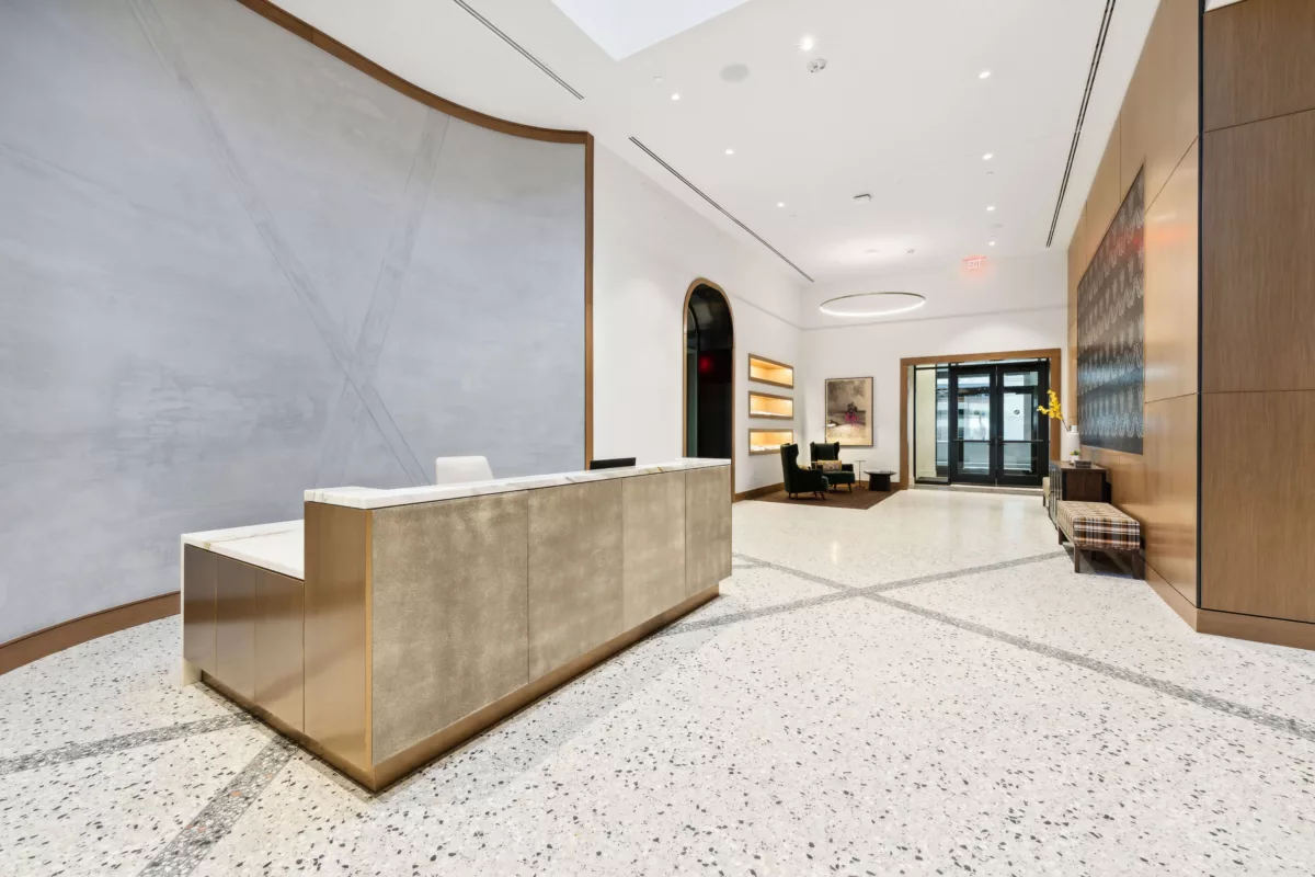 Concierge desk in from of gray wall with seating area in the background