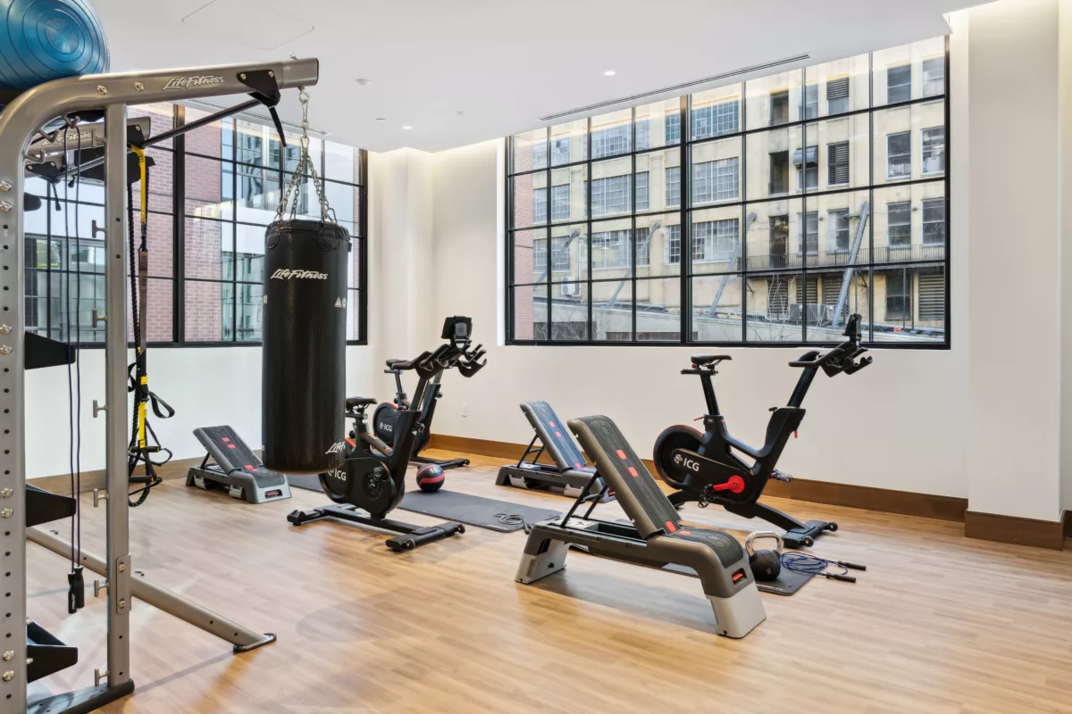 Fitness studio with large windows, wood-style floor, spin bikes, and exercise equipment