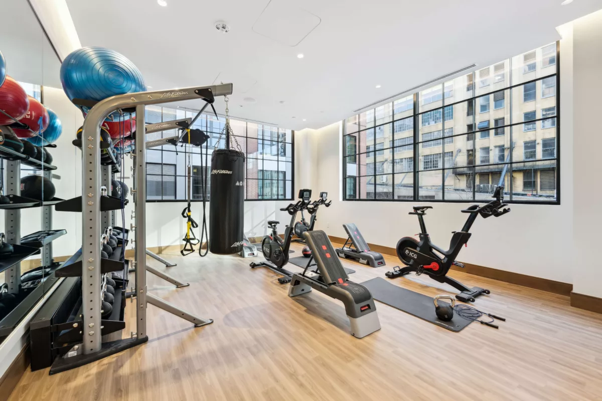 Fitness studio with large windows, wood-style floor, spin bikes, and exercise equipment