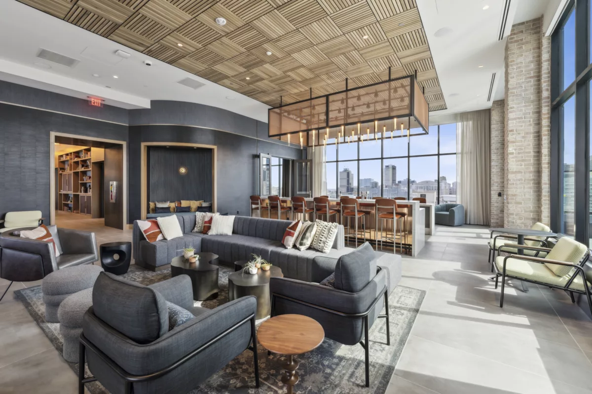 Rooftop lounge with bar, seating area with couches, and large windows with views of the city skyline