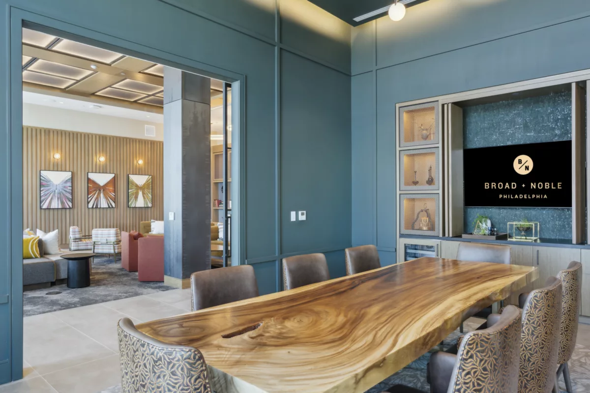 Rooftop private dining room with dark teal walls, long wooden table, chairs, and TV screen