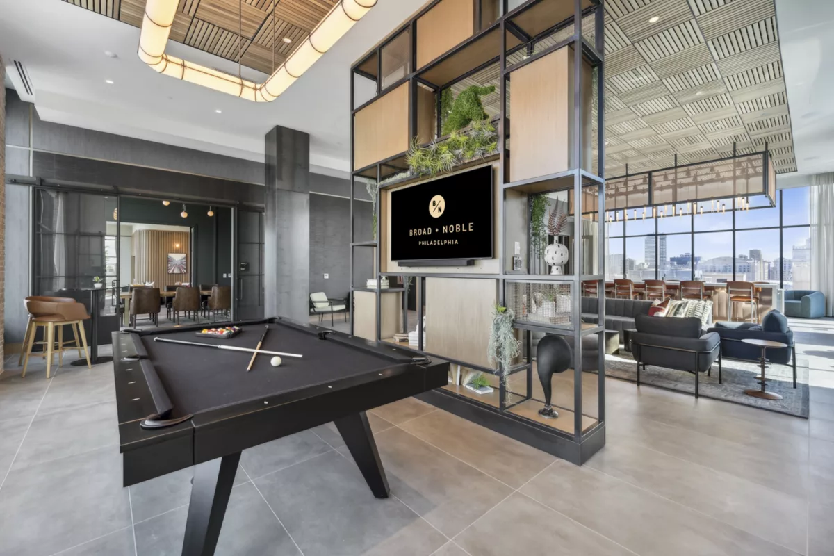Rooftop lounge with pool table, bar areas, and large windows with city views