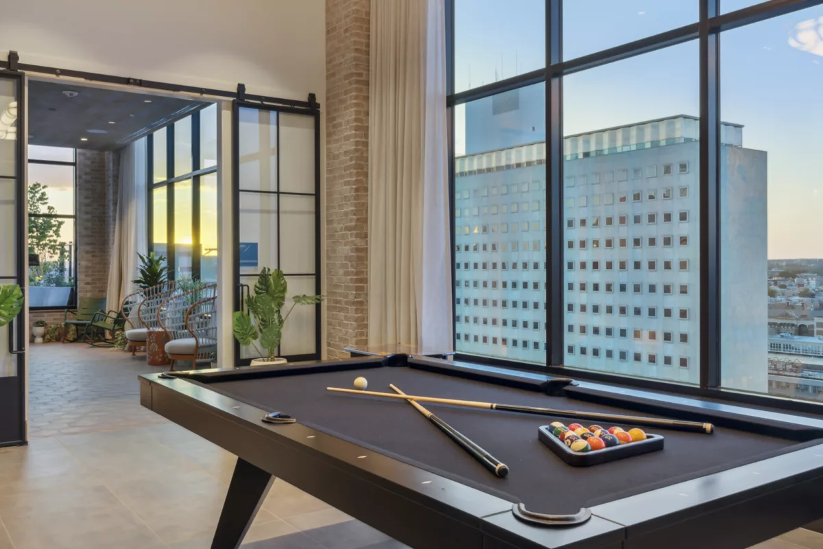 Rooftop lounge with pool table and large windows with city views