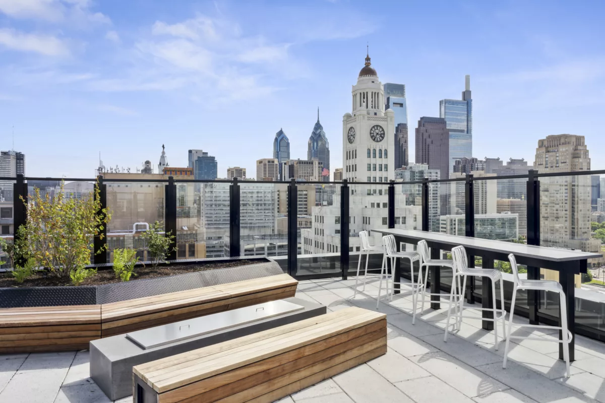 Rooftop deck with counter seating, benches, and city skyline views