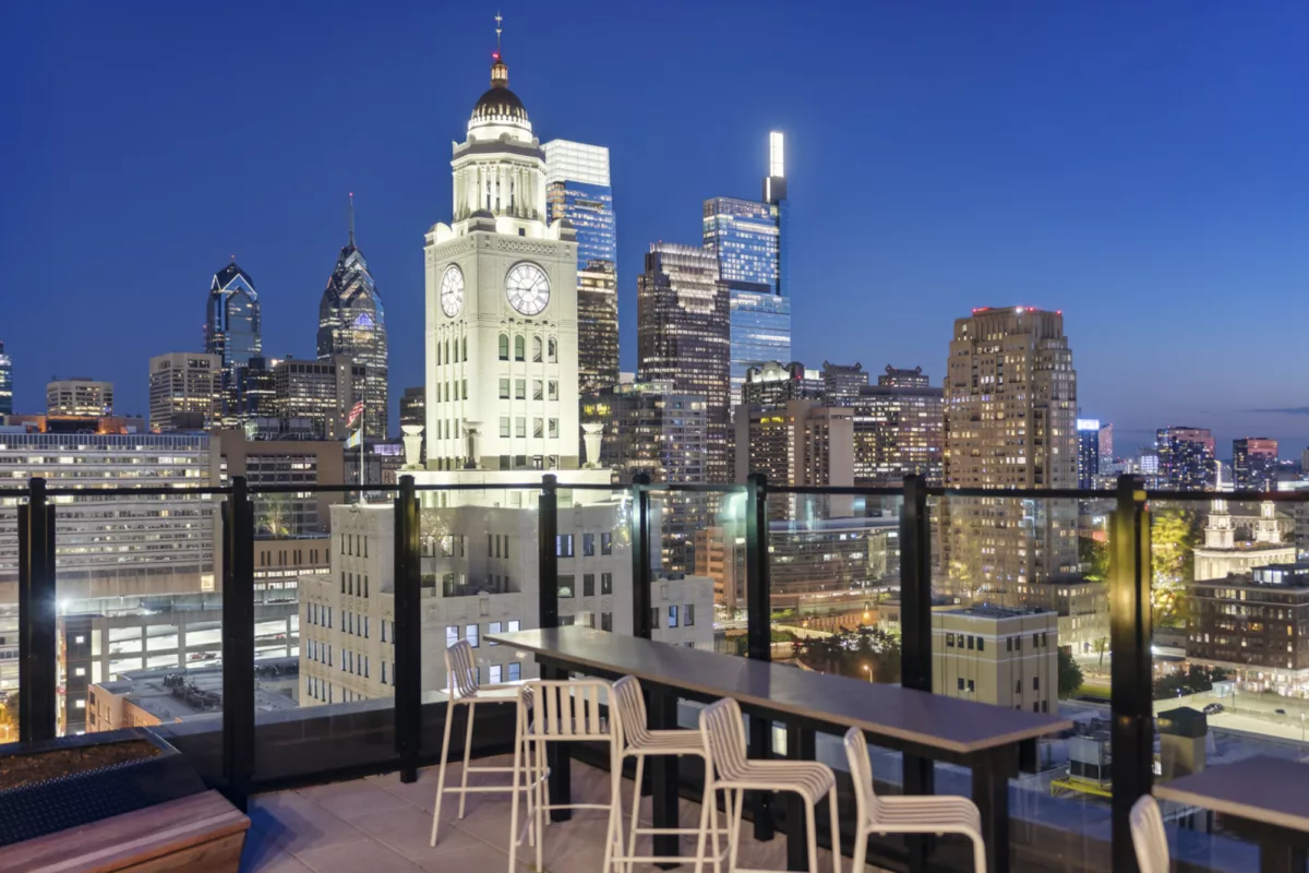 Rooftop deck at night with counter seating and city skyline views