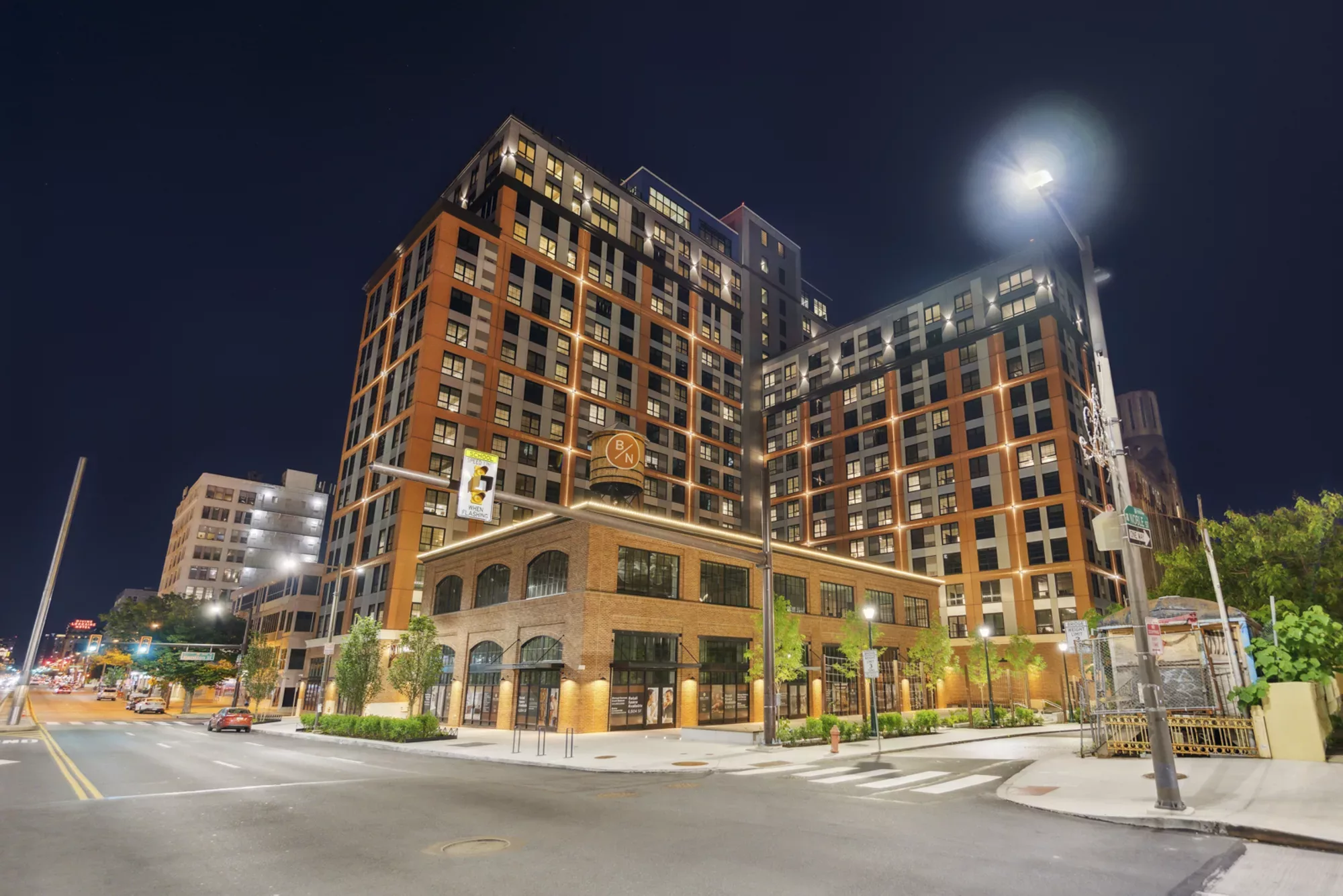 Exterior of Broad + Noble, an 18-story brick apartment building with a brick exterior, at night