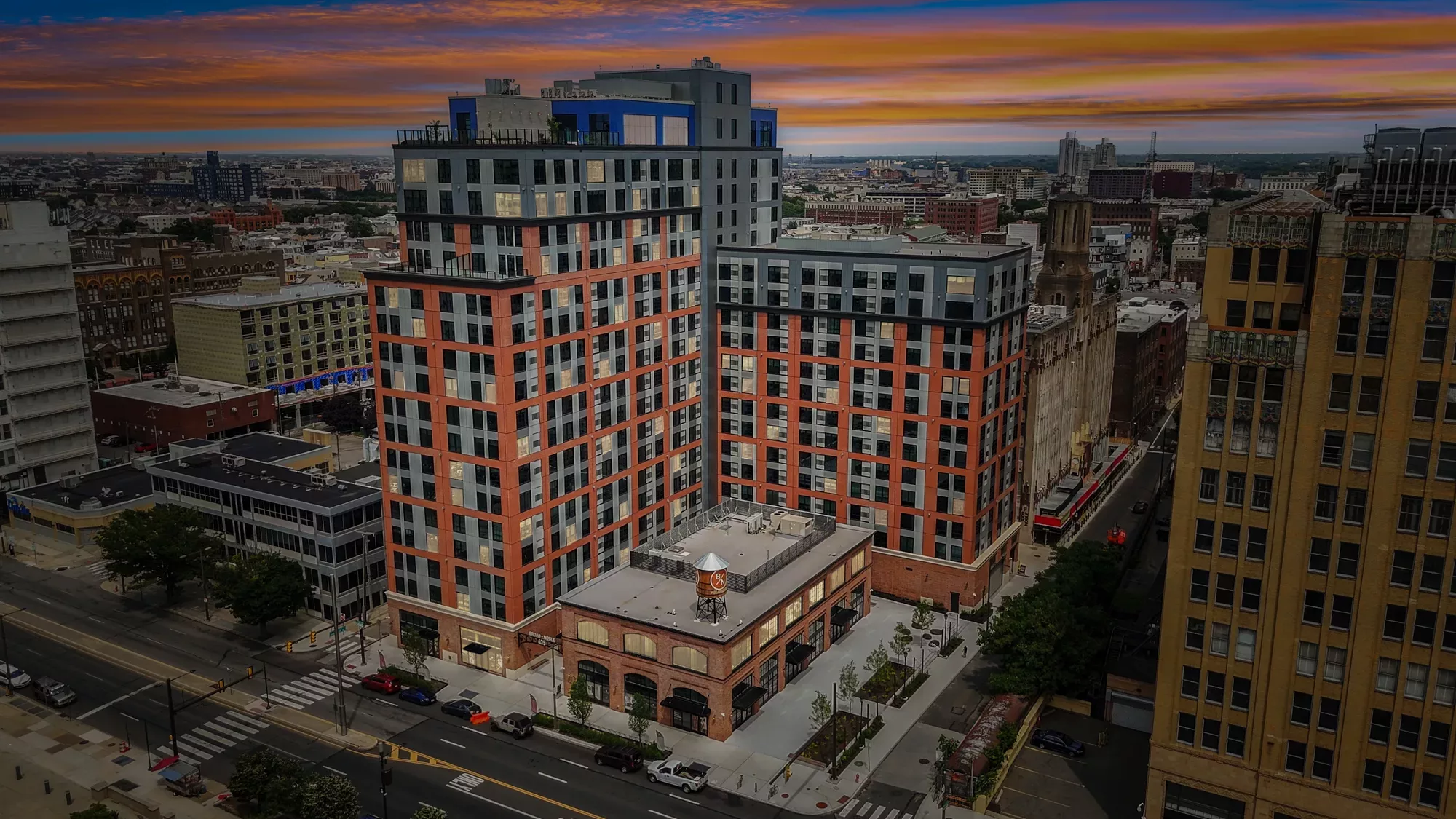 Exterior of Broad + Noble, an 18-story apartment building with a brick exterior, at dusk