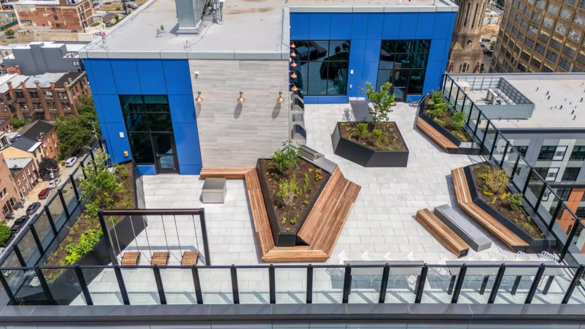 Rooftop deck with swings, grills, seating areas, and greenery
